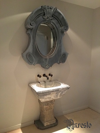 Italiaanse marmeren wasbak verfraaid met antieke ossenoog dienende als spiegel.